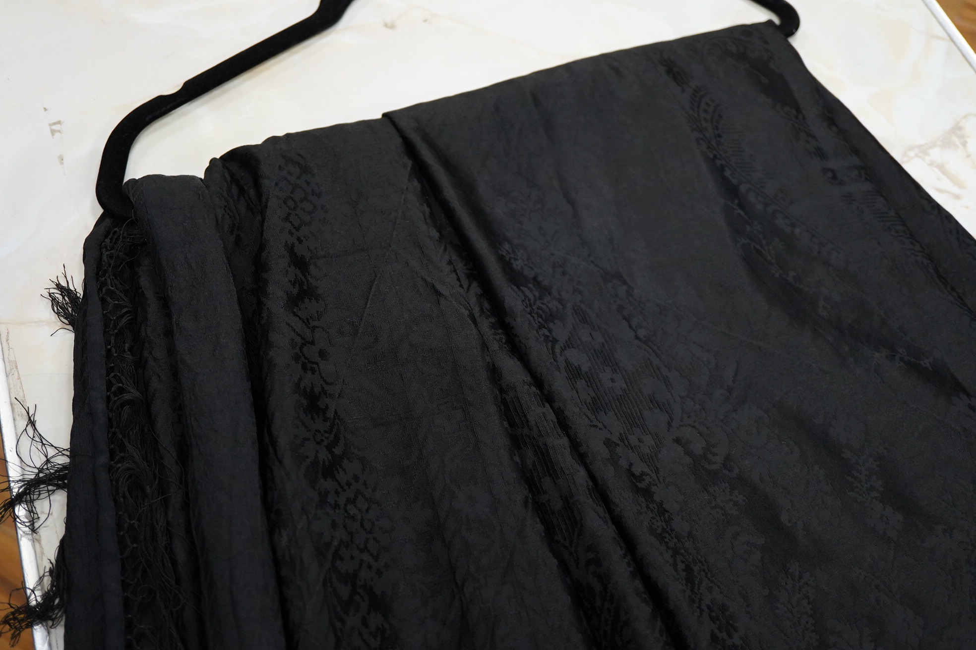 A Edwardian black silk damask paisley patterned shawl. Possibly a mourning shawl.178cm x 156cm. Condition - one small hole, otherwise good.